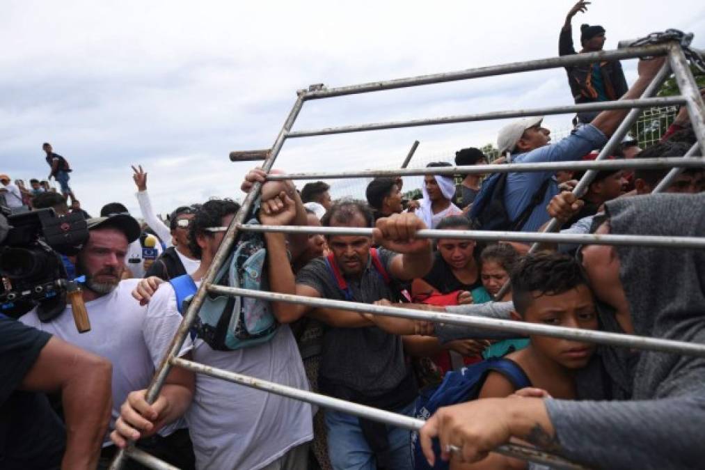 FOTOS: Así fue el momento en el que la caravana migrante de hondureños rompió los portones e ingresó a México