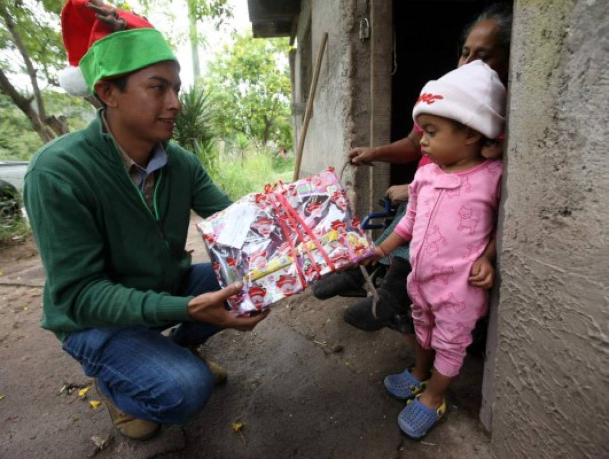 El periodista Elvis Mendoza entrega un juguete a la pequeña Amalia Matamoros, de dos años.Foto:Jimmy Argueta/EL HERALDO