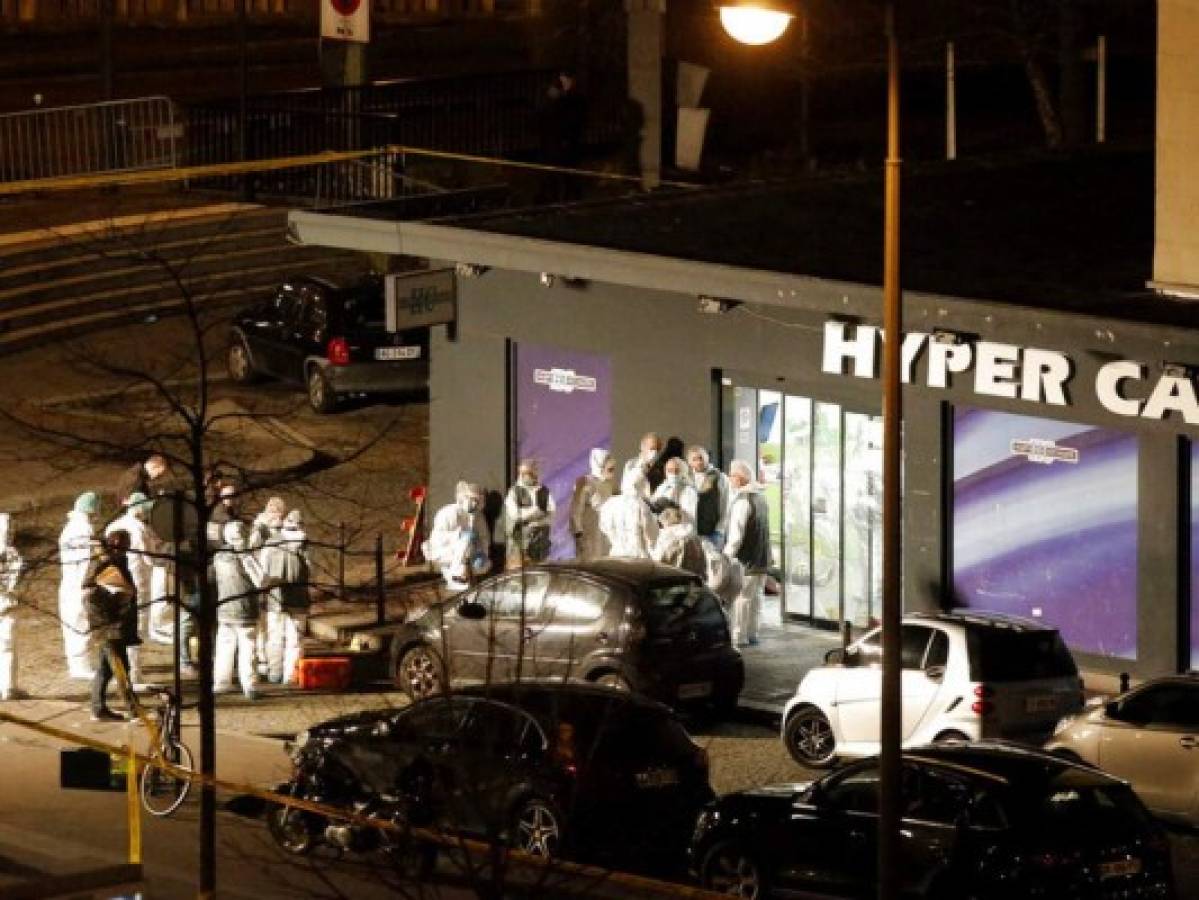 FILE - In this Jan. 9, 2015 file photo, forensic officers gather outside a kosher grocery store which was the scene of a hostage taking in Paris. The January 2015 attacks against Charlie Hebdo and, two days later, a kosher supermarket, touched off a wave of killings claimed by the Islamic State group across Europe. Seventeen people died along with the three attackers. Thirteen men and a woman accused of providing the attackers with weapons and logistics go on trial on terrorism charges Wednesday Sept. 2, 2020. (AP Photo/Francois Mori, File)