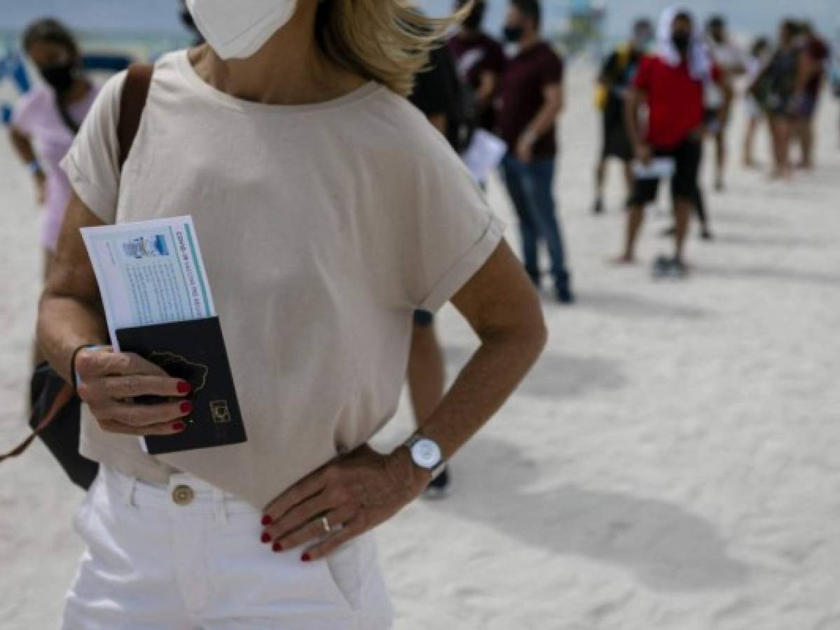 Con sus pasaportes en mano, los turistas hacen fila para vacunarse contra el covid-19. Foto AFP