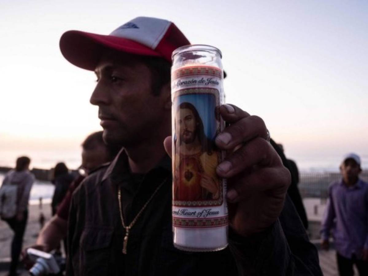 Un migrante sostiene una candela durante la vigilia en memoria a sus compañeros muertos. Foto: Agencia AFP.