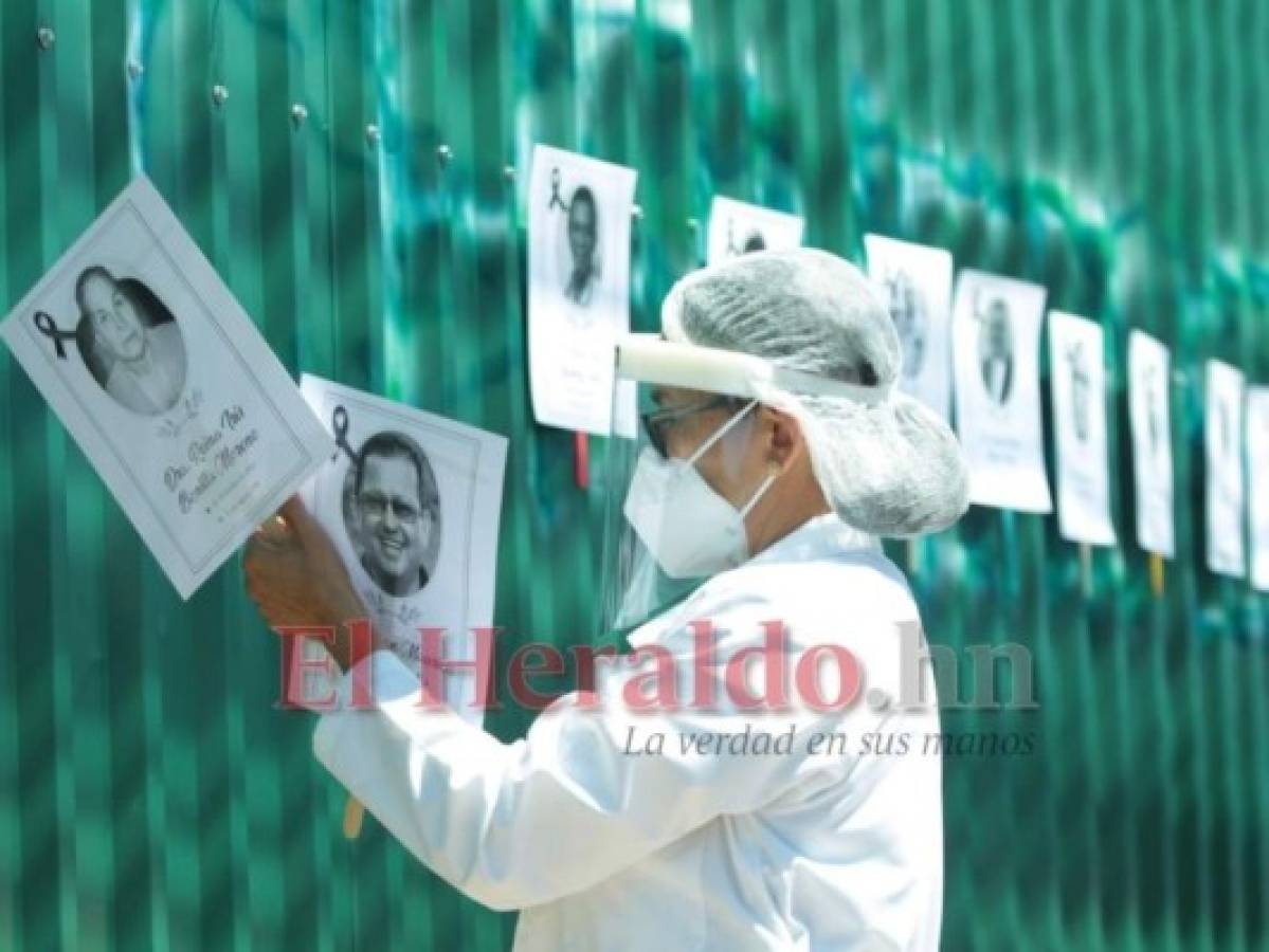 Una doctora coloca en un cerco los rostros de sus compañeros muertos por la pandemia. Foto: Alex Pérez/ EL HERALDO