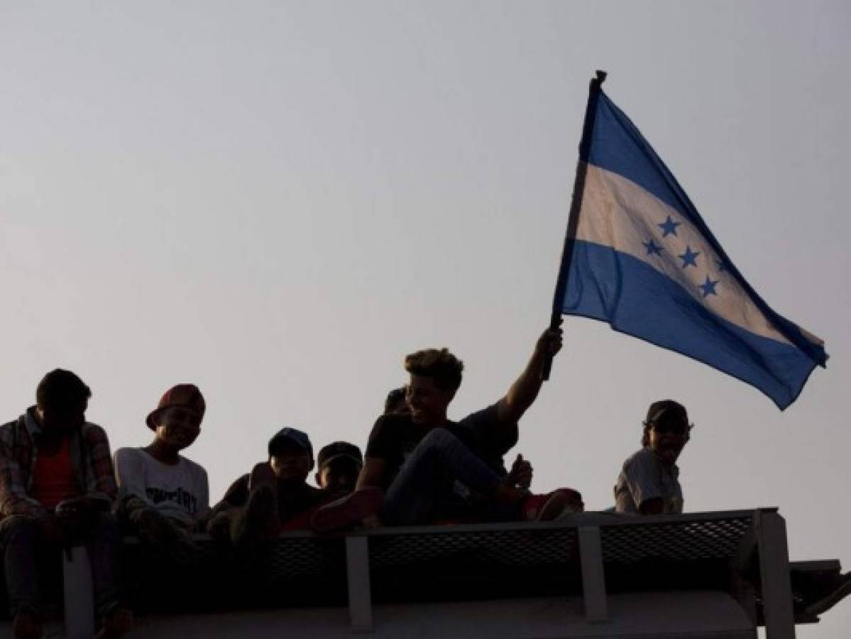 Honduran migrants flying their country's flag, ride atop a freight train during their journey toward the US-Mexico border, in Ixtepec, Oaxaca State, Mexico, Tuesday, April 23, 2019. The once large caravan of about 3,000 people was essentially broken up by an immigration raid on Monday, as migrants fled into the hills, took refuge at shelters and churches or hopped passing freight trains. (AP Photo/Moises Castillo)