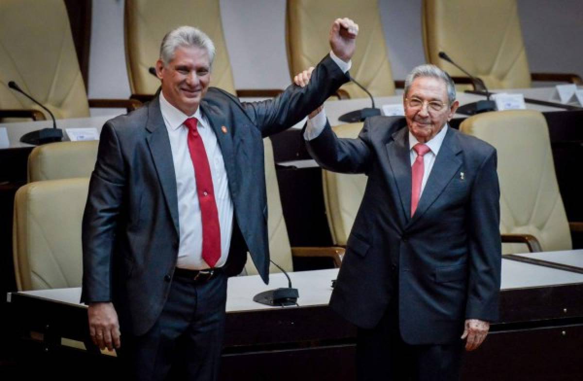 El presidente cubano saliente, Raúl Castro, levanta el brazo del nuevo presidente de Cuba, Miguel Díaz-Canel, después de haber sido nombrado formalmente por la Asamblea Nacional, en La Habana. Foto AFP