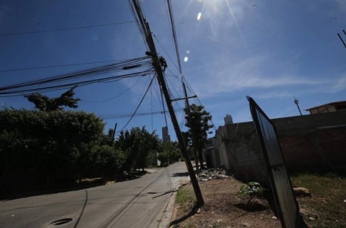 Alcantarilla abierta, poste inclinado y basura en Tepeyac