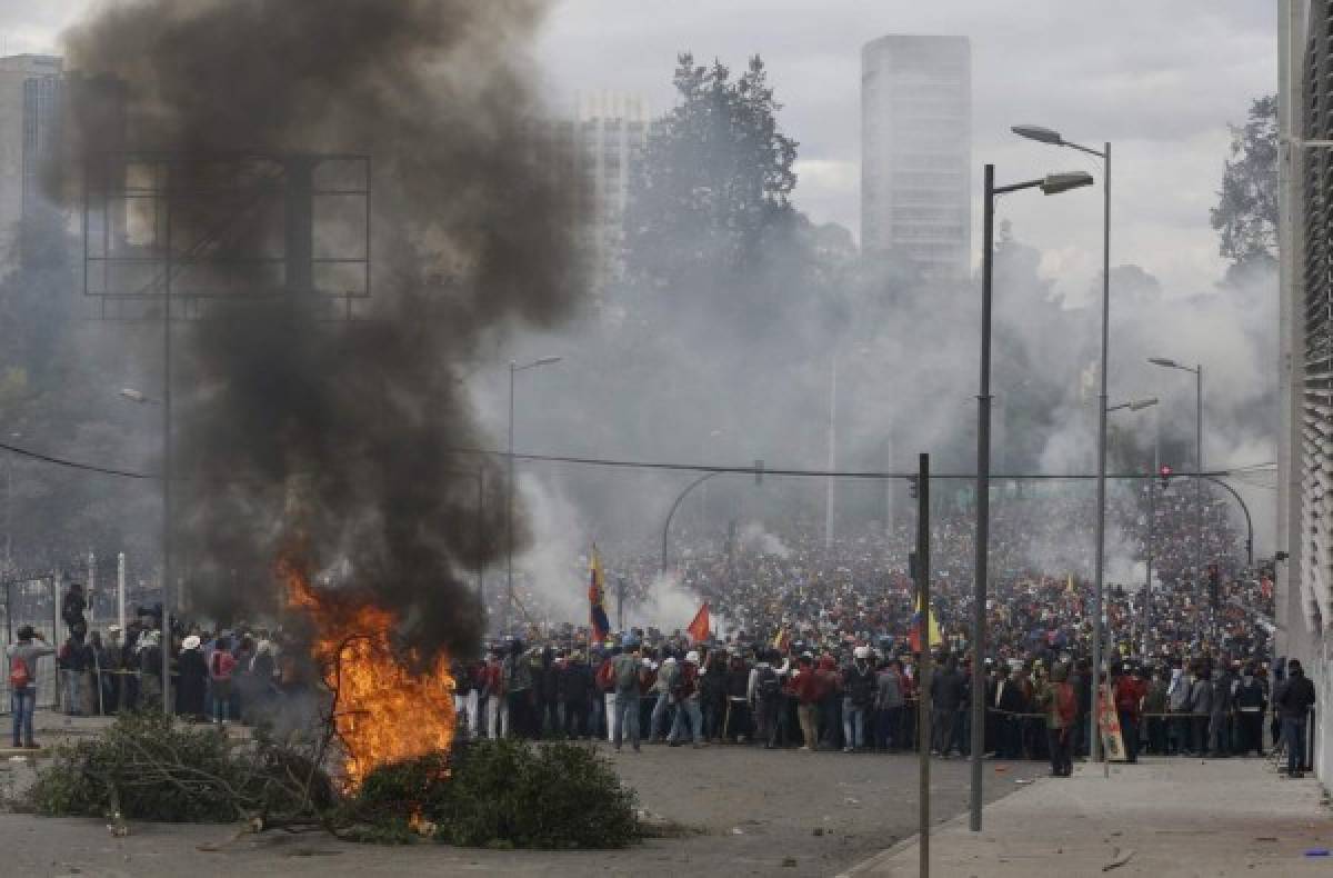 Manifestantes contra el gobierno se reúnen detrás de una barricada que arde durante una protesta que rechaza las políticas económicas del presidente Lenín Moreno en Quito, Ecuador, el artes 8 de octubre de 2019. (AP Foto/Fernando Vergara)