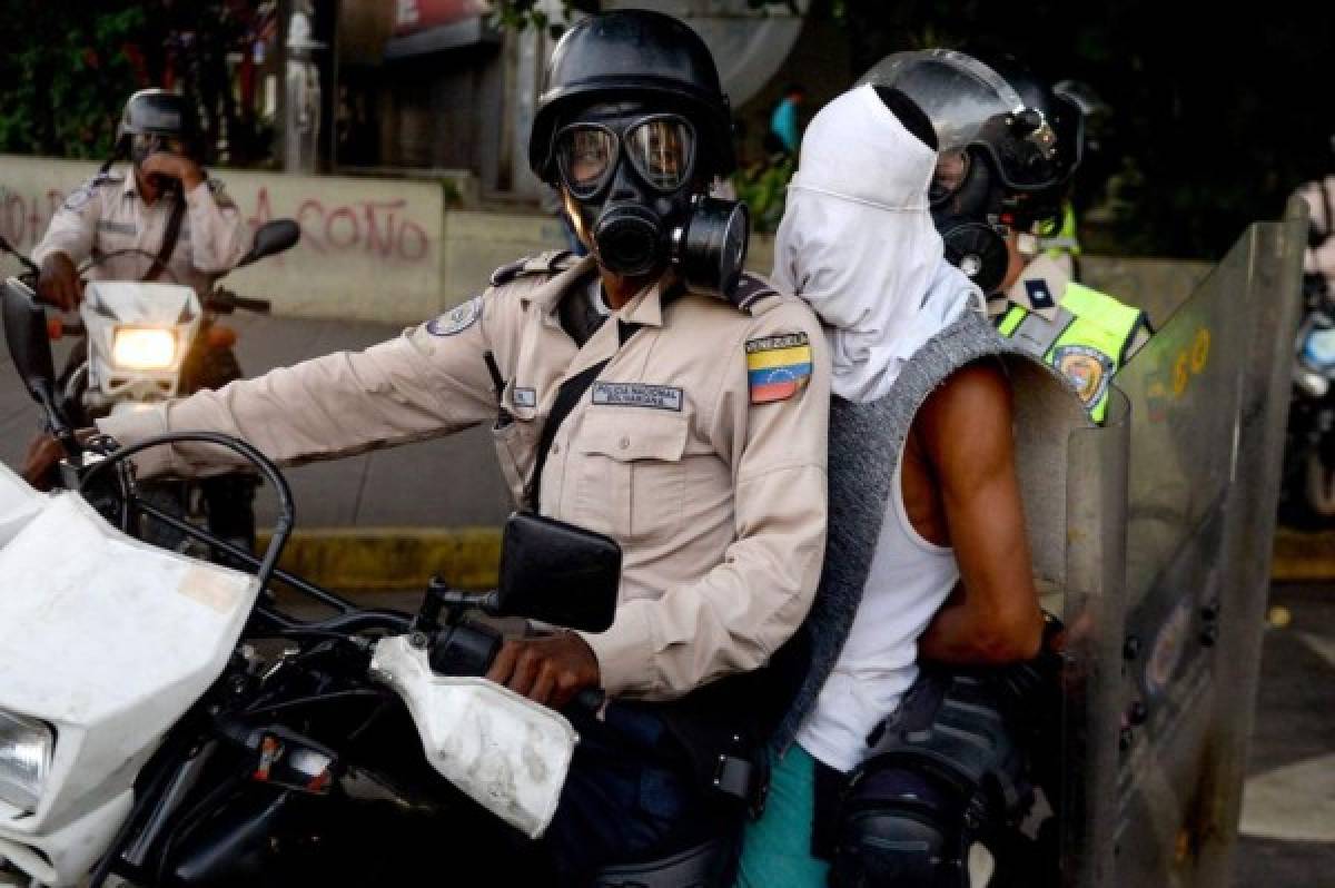 Police take a protester into custody as opposition activists demonstrating against the government of Venezuelan President Nicolas Maduro clash with riot police in Caracas on June 26, 2017. A political and economic crisis in the oil-producing country has spawned often violent demonstrations by protesters demanding Maduro's resignation and new elections. The unrest has left 75 people dead since April 1. / AFP PHOTO / FEDERICO PARRA