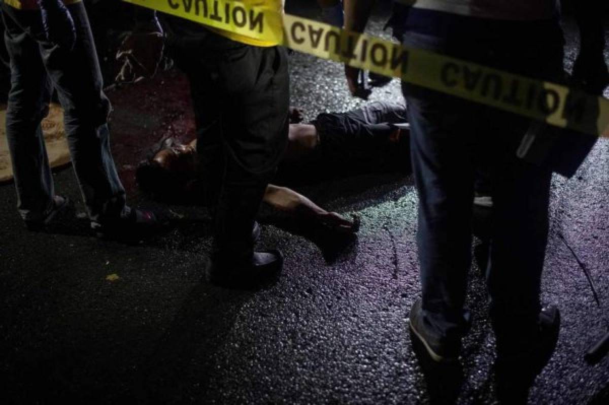This picture taken on May 18, 2017, shows police officers investigating an alleged drug dealer killed by unidentified gunman in Manila.President Rodrigo Duterte swept to an election victory last year largely on a pledge to wipe out his nation's illegal drugs trade within three to six months, saying he would do so by killing thousands of people. Duterte fulfilled his vow on the death toll, drawing condemnation from rights groups who warned he may be orchestrating a crime against humanity as police and unknown assassins filled slums with bullet-ridden corpses. / AFP PHOTO / NOEL CELIS