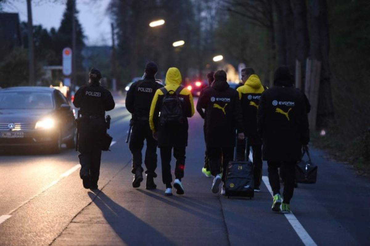 Police escort Dortmund's players after the team bus of Borussia Dortmund had some windows broken by an explosion some 10km away from the stadium prior to the UEFA Champions League 1st leg quarter-final football match BVB Borussia Dortmund v Monaco in Dortmund, western Germany on April 11, 2017. / AFP PHOTO / PATRIK STOLLARZ