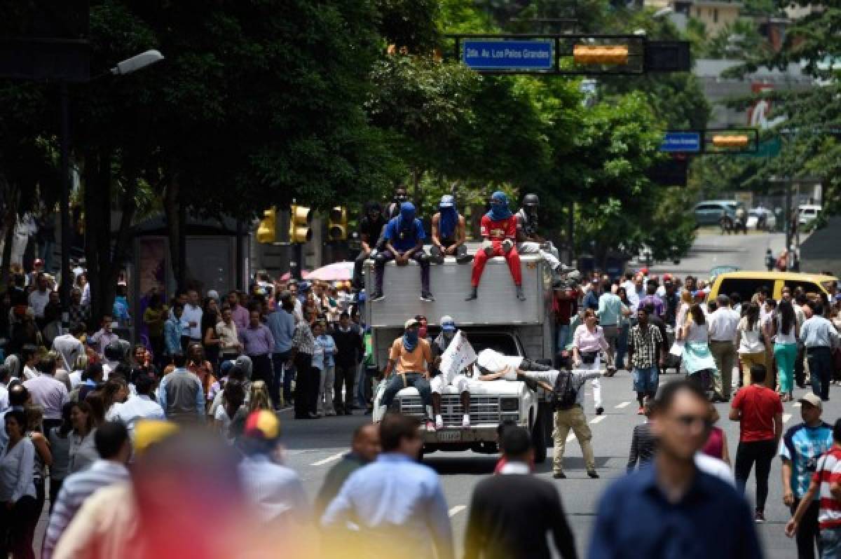Opposition activists block an avenue in Caracas as they demonstrate against the government of President Nicolas Maduro, on June 26, 2017.A political and economic crisis in the oil-producing country has spawned often violent demonstrations by protesters demanding Maduro's resignation and new elections. The unrest has left 75 people dead since April 1. / AFP PHOTO / Juan BARRETO