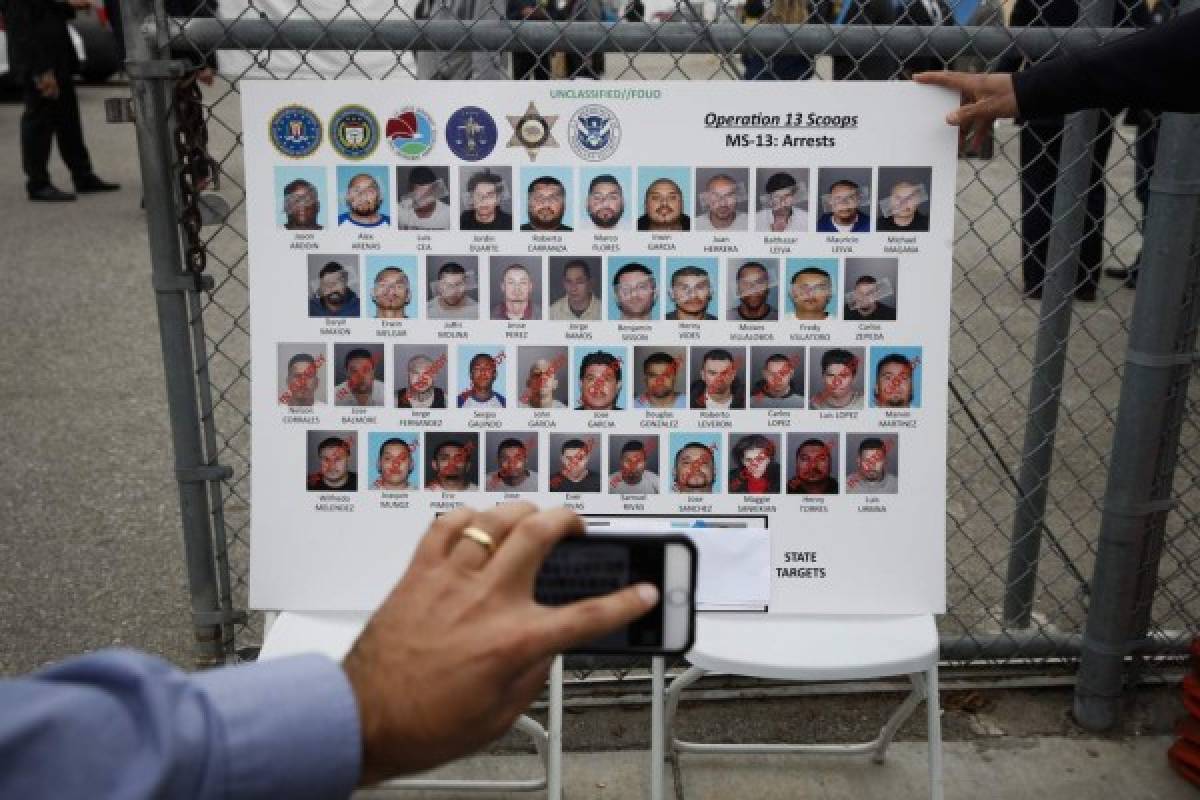 A reporter uses his smartphone to photograph a board showing images of MS-13 gang members during a news conference Wednesday, May 17, 2017, in Los Angeles. Hundreds of federal and local law enforcement fanned out across Los Angeles, serving arrest and search warrants as part of a three-year investigation into the violent and brutal street gang MS-13. (AP Photo/Jae C. Hong)