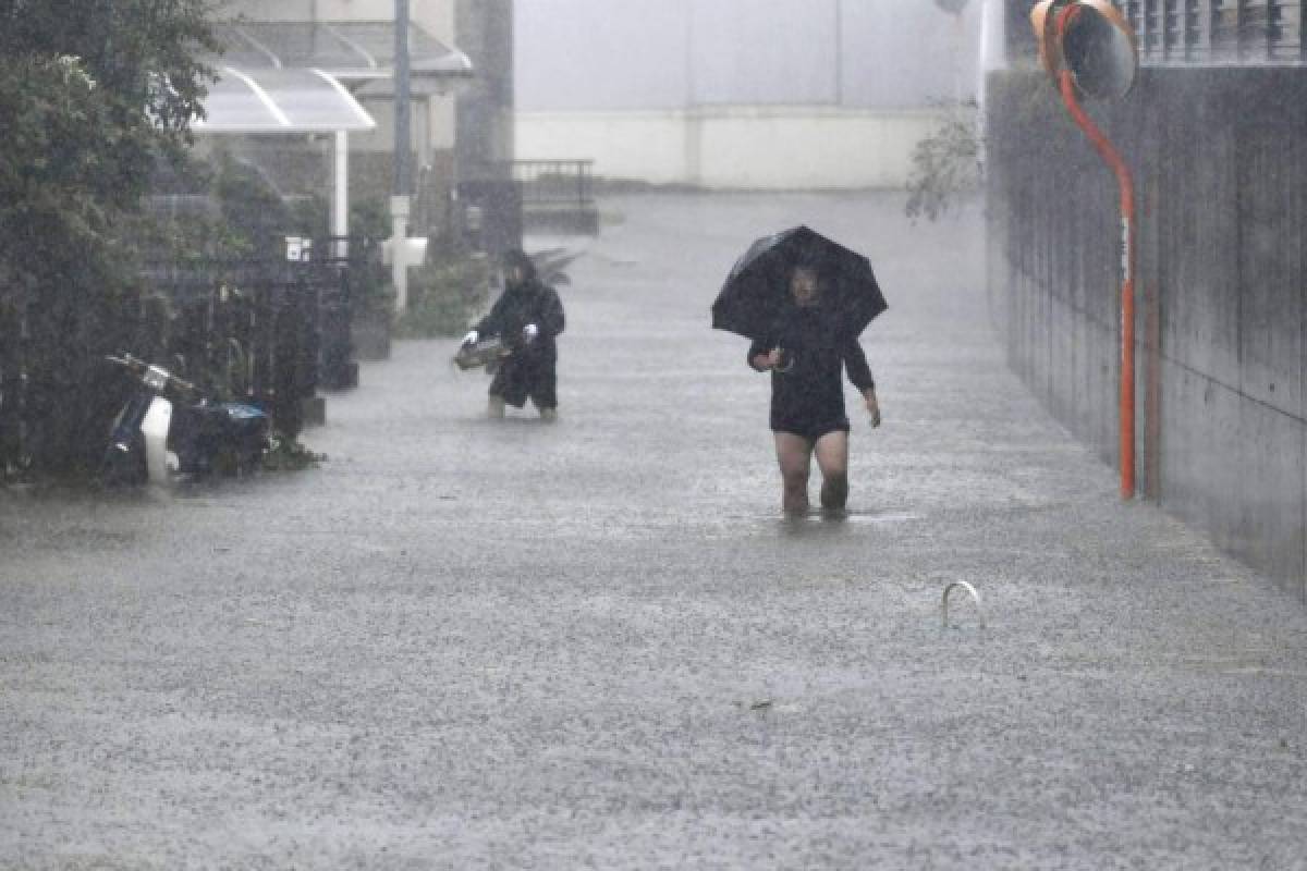 Personas caminan en una calle inundada a consecuencia del tifón Hagibis, en Shizuoka, centro de Japón, el sábado 12 de octubre de 2019. (Kyodo News vía AP)