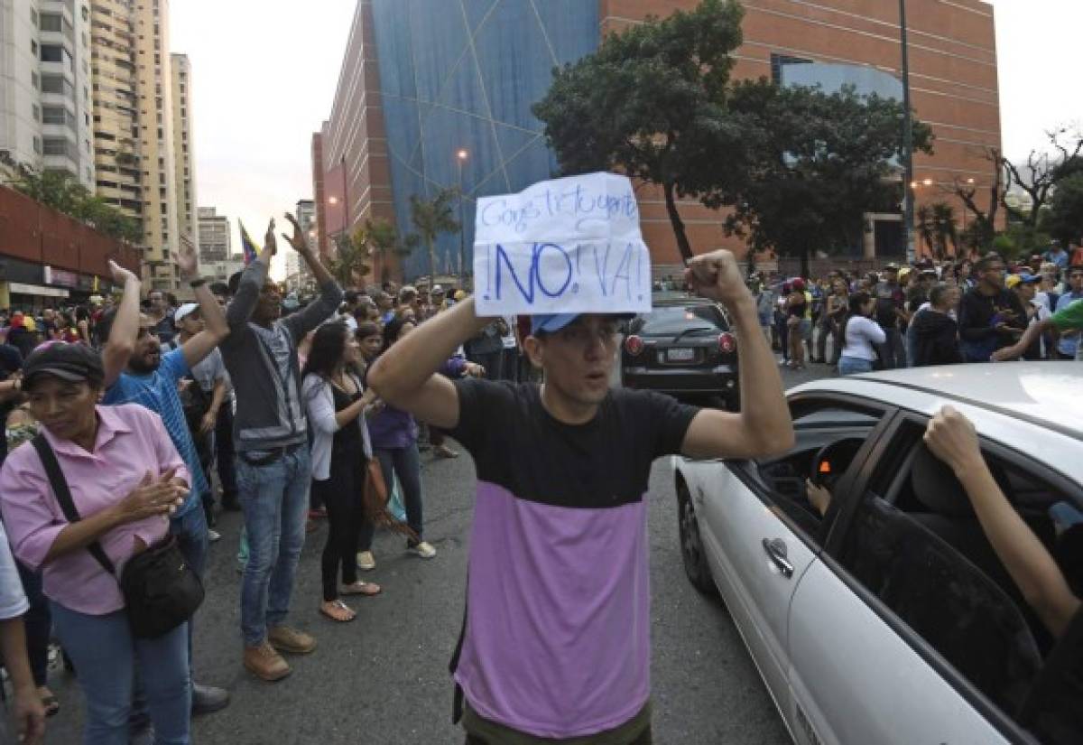 People demonstrate in Caracas on July 16, 2017 as they take part in an opposition-organized vote to measure public support for Venezuelan President Nicolas Maduro's plan to rewrite the constitution.Authorities have refused to greenlight the vote that has been presented as an act of civil disobedience and supporters of Maduro are boycotting it. Protests against Maduro since April 1 have brought thousands to the streets demanding elections, but has also left 96 people dead, according to an official toll. / AFP PHOTO / JUAN BARRETO