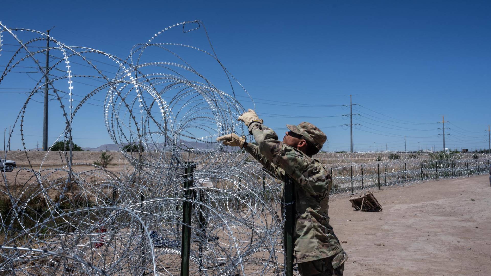 $!Un soldado de la Guardia Nacional de Texas coloca alambre de púas a lo largo de la frontera entre EU y México en El Paso.