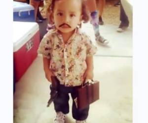 Con un bigote falso, un arma al cinto, el cabello peinado hacia un lado y un maletín lleno de billetes, el pequeño simula ser Pablo Escobar pero se cree que por su corta edad no sabe a quién representa, pero los adultos que lo acompañan sí.