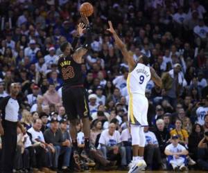 LeBron James # 23 de los Cleveland Cavaliers tira sobre Andre Iguodala # 9 de los Golden State Warriors durante un partido de baloncesto de la NBA en el ORACLE Arena. Agencia AFP.