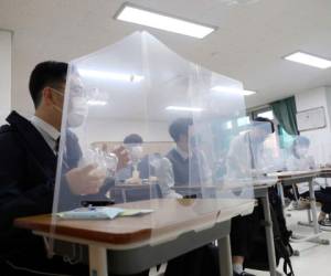 Estudiantes de último curso de secundaria esperan a que comience su clase, con mamparas en sus mesas en la Escuela Secundaria Jeonmin en Daejeon, Corea del Sur. Cientos de miles de estudiantes volvían a sus clases en Corea del Sur, en el inicio de la 'nueva normalidad' tras las cuarentenas por el coronavirus. (Kim Jun-beom/Yonhap via AP)