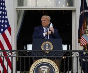 El presidente Donald Trump se retira su mascarilla el sábado 10 de octubre de 2020 para pronunciar un discurso desde el balcón del Salón Azul de la Casa Blanca, en Washington. (AP Foto/Alex Brandon).