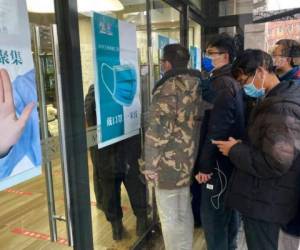 Residentes hacen fila para recibir la vacuna contra el covid-19 cerca de un cartel con el lema 'Eviten aglomeraciones', en Beijing, el 12 de enero de 2021. Foto: AP