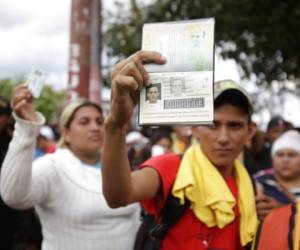 Edwin Antonio Garcia Cruz muestra su pasaporte mientras otra migrante alza su tarjeta de identidad para pedir los dejen pasar a Esquipulas, Guatemala. (Foto: AP)