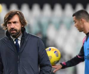 El entrenador italiano de la Juventus, Andrea Pirlo, camina sobre la cancha mientras el delantero portugués de la Juventus, Cristiano Ronaldo (R), calienta antes del partido de fútbol de la Serie A.