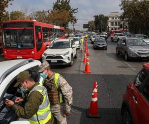 Los soldados verifican los permisos de tránsito de los viajeros en un puesto de control en Santiago de Chile, en medio de la pandemia de coronavirus. Las autoridades anunciaron el restablecimiento de un bloqueo en toda la ciudad para ayudar a contener la propagación del COVID-19. (Foto AP/Esteban Félix)