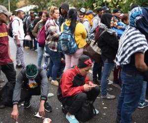 Decenas de personas dispersas en grupos caminan a la orilla de la carretera, mientras que otras son transportadas en la parte trasera de pick-ups. Foto / AFP