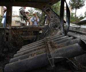 Combatientes talibanes investigan un automóvil dañado después de que se dispararan múltiples cohetes en Kabul el lunes 30 de agosto. FOTO: AFP