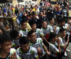 Doce niños y su entrenador de fútbol, Ekkapol Chantawong, rescatados dramáticamente de lo más profundo de una cueva tailandesa después de estar atrapados durante más de dos semanas, saludan al llegar a una conferencia de prensa en Chiang Rai el 18 de julio de 2018, tras ser dados de alta del hospital. Foto AFP