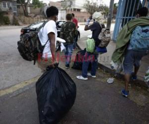 Un grupo de migrantes carga varias bolsas después de ser retornados desde México a Honduras. Los compatriotas viajaban hacia Estados Unidos, pero fueron devueltos desde el país azteca. Foto: Emilio Flores/ EL HERALDO.