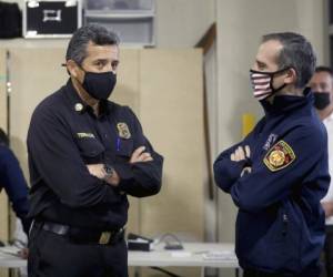 El jefe del Departamento de Bomberos de Los Ángeles, Ralph M. Terrazas (izquierda) y el alcalde de Los Ángeles, Eric Garcetti, hablando mientras personal del Departamento de Bomberos recibe la vacuna de Moderna contra el covid-19. Foto: AP.