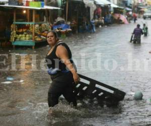 El torrencial aguacero duró unos 20 minutos y dejó las calles de Comayagüela inundadas. Una vendedora rescata su mercadería. Foto David Romero