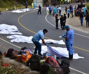 Trabajadores forenses cubren los cadáveres de pasajeros muertos en un autobús que chocó con un camión remolque en Gualan, Guatemala, el sábado 21 de diciembre. Foto: Carlos Cruz/AP.