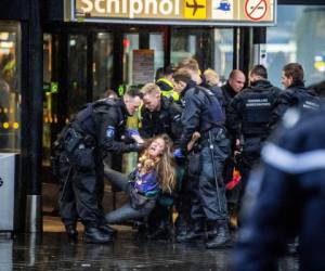 Los oficiales de la policía holandesa real escoltan a un activista de Greenpeace durante una protesta para denunciar la contaminación de las aerolíneas en la sala principal del aeropuerto Schiphol de Amsterdam. Foto: AFP