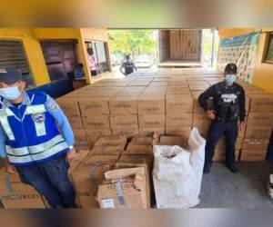 Agentes de la Policía Nacional vigilan el fuerte cargamento de cigarillos que fue decomisado en Puerto Cortés.