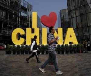 En esta imagen, un hombre come un tentempié mientras pasa por delante de una escultura con el lema 'I love China' ('Amo China') en un popular centro comercial en Beijing, China. Foto:AP