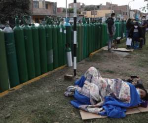 Gente tumbada junto a sus botellas vacías de oxígeno mientras esperan a llenarlas en un comercio de Callao, Perú, son las imágenes que deja la crisis por oxígeno. (AP Foto/Martin Mejia)