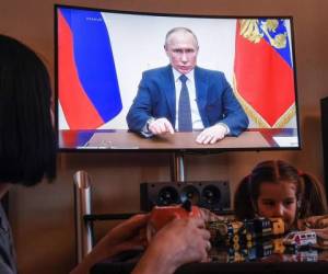 Una mujer mira una transmisión en vivo del discurso del presidente ruso Vladimir Putin a la nación sobre el brote de coronavirus, en su departamento en Moscú. Foro: Agencia AFP.