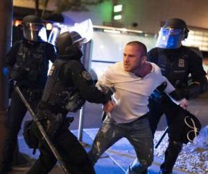 El domingo por la noche, cientos de manifestantes antirracistas se reunieron frente a la sede de la policía en el centro de Portland, levantando pancartas y lanzando en ocasiones proyectiles.