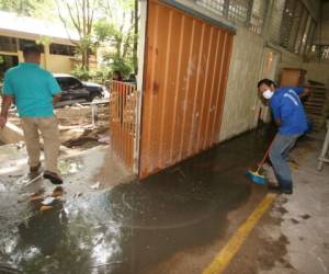 Los empleados del Instituto Técnico Honduras debieron sacar el agua contaminada de las instalaciones afectadas. Para ello utilizaron botas de plástico y mascarillas para su protección. Foto: Efraín Salgado / EL HERALDO.