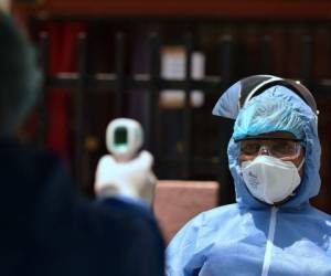 A Health worker wearing a biosafety suit takes the temperature of a nurse during a checkup for the novel coronavirus, COVID-19, at Nueva Floresta neighbourhood in Cali, Colombia, on April 20, 2020. - More than 160,000 people have died from the new coronavirus around the world according to an AFP tally at 0940 GMT Sunday based on official sources. (Photo by Luis ROBAYO / AFP)