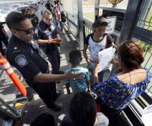 En esta fotografía de archivo del 17 de julio de 2019, un agente de la Oficina de Aduanas y Protección Fronteriza verifica los documentos de migrantes antes de que sean llevados a solicitar asilo en Estados Unidos, en el Puente Internacional 1 en Nuevo Laredo, México. Fotos: Agencia AP.