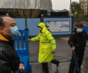 Los guardias se paran en una entrada mientras los miembros del equipo de la Organización Mundial de la Salud (OMS), que investigan los orígenes del coronavirus covid-19, llegan al mercado mayorista cerrado de Huanan Seafood en Wuhan, provincia central de Hubei en China, el 31 de enero de 2021.