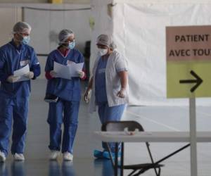 Medical staff wearing protective gear talks inside a new COVID-19 diagnose center in a gymnasium on march 23, 2020, in Taverny, on March 22, 2020, on the seventh day of a lockdown aimed at curbing the spread of the COVID-19 (novel coronavirus) in France. (Photo by Ludovic MARIN / AFP)