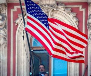 Un empleado del consulado de EE. UU., en San Petersburgo, Rusia, retira la bandera de su país tras la expulsión masiva de diplomáticos estadounidenses. (Foto: AFP)