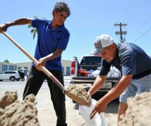 Leo Sermiento y Emilio Gutierrez, llenan sacos de arena en South Padre Island, Texas. por la posible llegada del Huracán Harvey. (Jason Hoekema/The Brownsville Herald via AP).