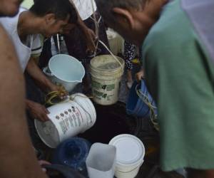 El 1 de abril de 2019, en el municipio de El Valle, en Caracas, la gente extrae agua de una alcantarilla para usarla en sus inodoros. Foto AFP