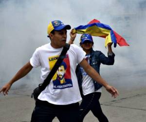 Manifestantes en Caracas se cubren ante un ataque con gases de parte de la Guardia Nacional Bolivariana. Foto: Agencia AFP.
