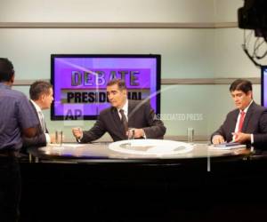 Fabricio Alvarado, del Partido Restauración Nacional, a la izquierda, participa en un debate con su rival del oficialista Partido Acción Ciudadana, Carlos Alvarado, a la derecha, mientras al centro se observa al moderador, el periodista Ignacio Santos. (AP Foto/Arnulfo Franco)