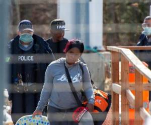 En esta fotografía del 18 de marzo de 2020, unos solicitantes de asilo cruzan la frontera de Nueva York a Canadá, en Hemmingford, Canadá. Foto: AP